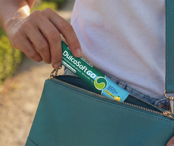 Stick monodose di DulcoSoft® GO Soluzione Orale pronta da bere che viene estratto da una borsetta per un'assunzione pratica fuori casa
